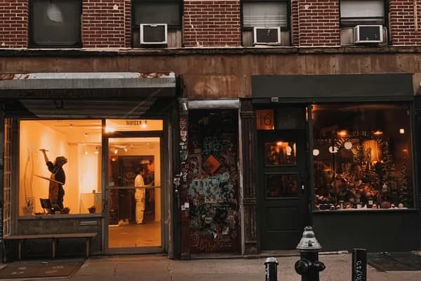 Illuminated storefront windows on brick building facade at dusk