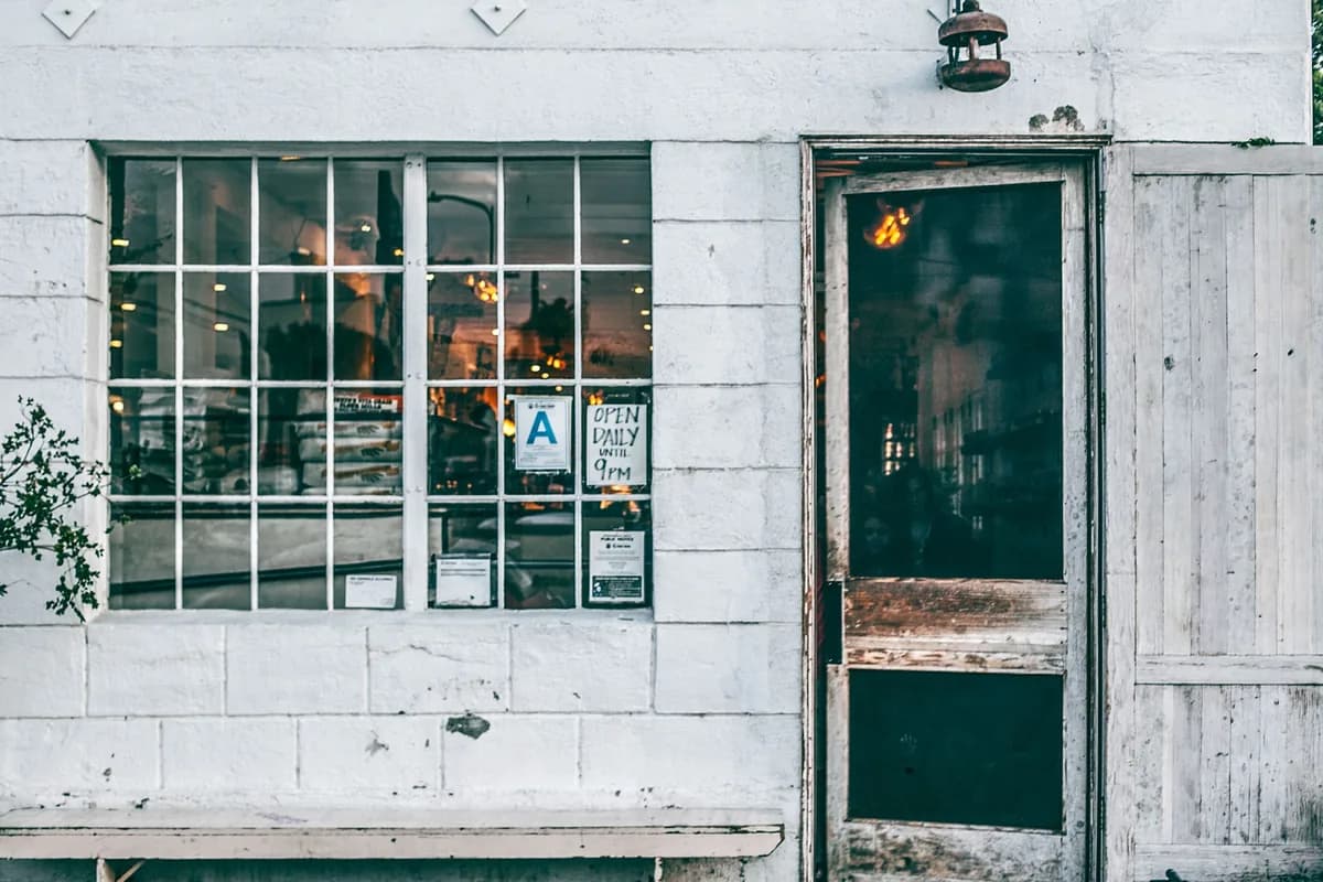 storefront window with grid panes and weathered green entry door beside