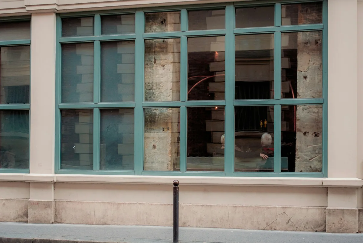 Turquoise-framed windows on historic stone building facade with dirty glass