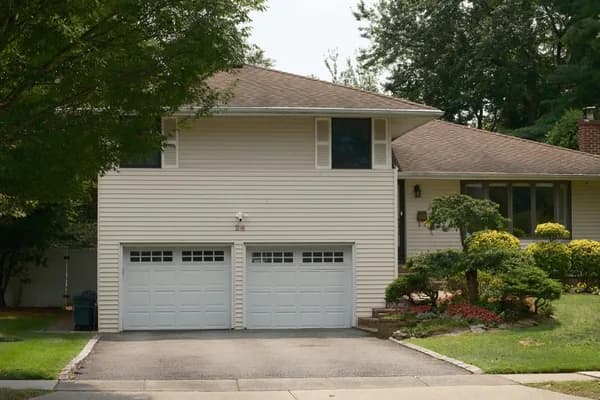 Two-story residential home with white siding and clean windows and garage doors