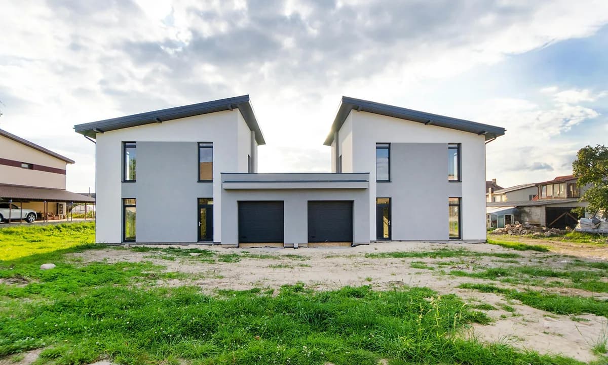 Modern two-story white house with black garage doors and large windows