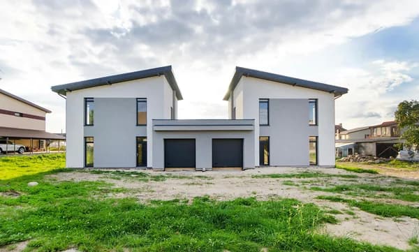 Modern two-story white house with black garage doors and large windows