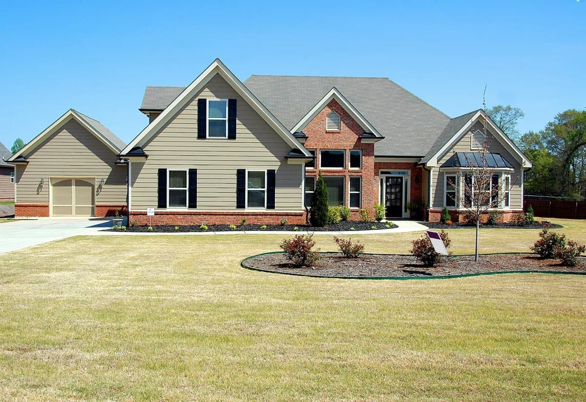 Large brick and siding residential home with multiple windows and manicured lawn