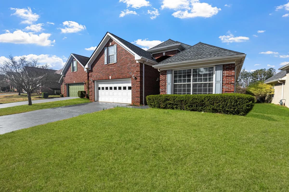 Brick residential house with large windows and manicured lawn