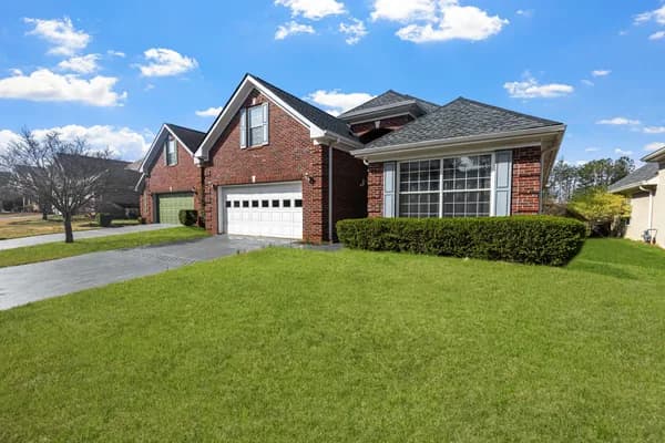 Brick residential house with large windows and manicured lawn