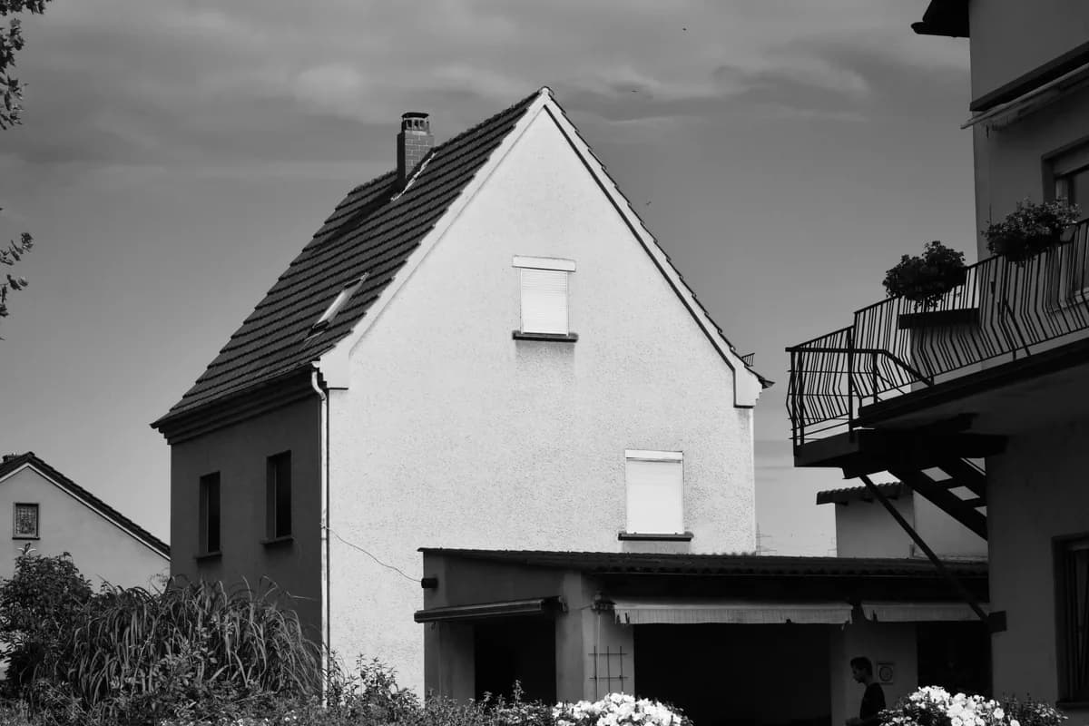 White house with dark roof and shuttered windows, residential exterior