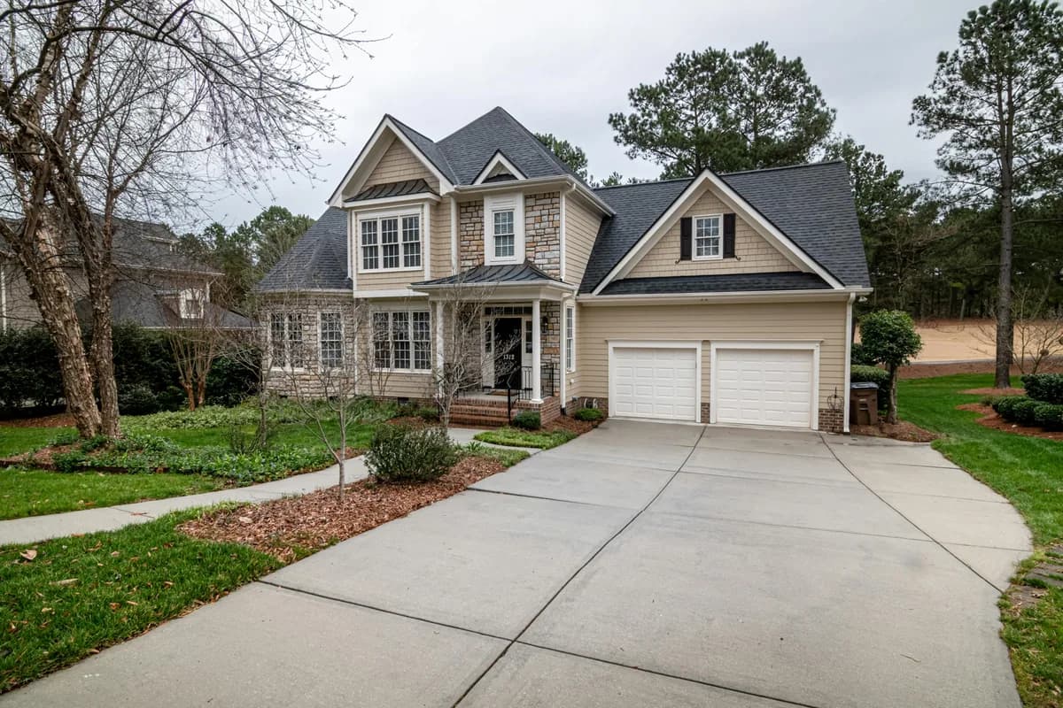 Two-story residential home with white garage doors and multi-pane windows