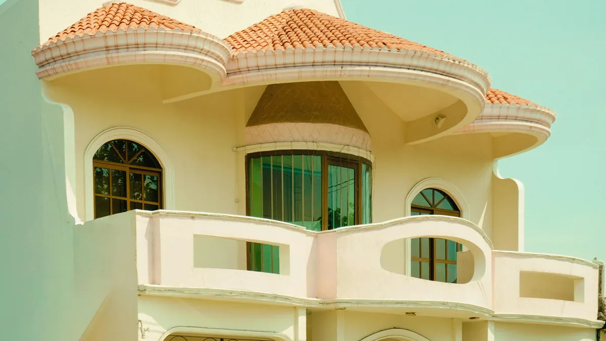 Mediterranean-style building exterior with curved balcony and green-trimmed windows