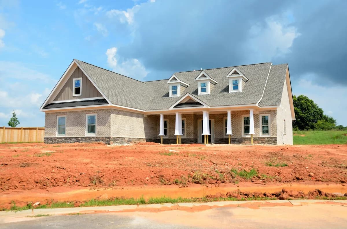 New brick home with white columns and dormer windows under construction