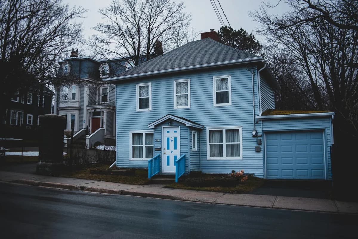 Blue residential house with white-trimmed windows and attached garage