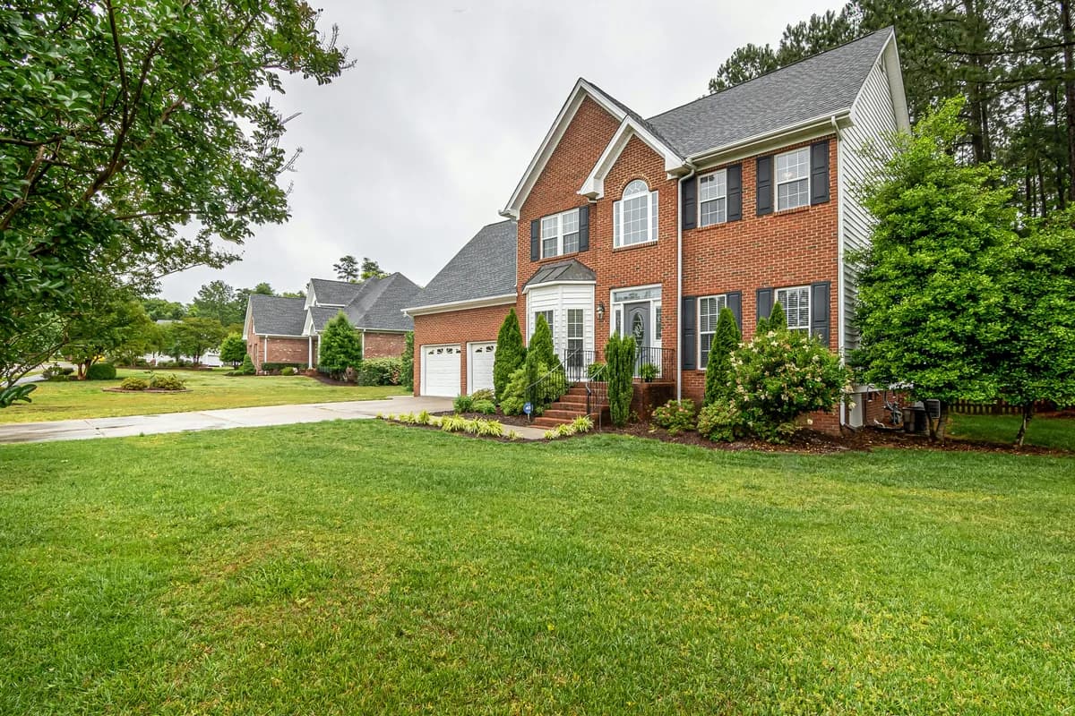 Brick residential home with manicured lawn and landscaping, no visible window cleaning activity