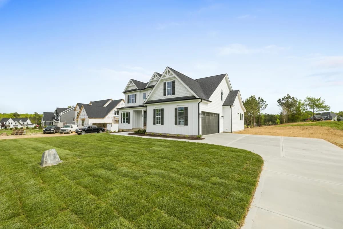 Modern white two-story house with dark roof and attached garage on landscaped lot