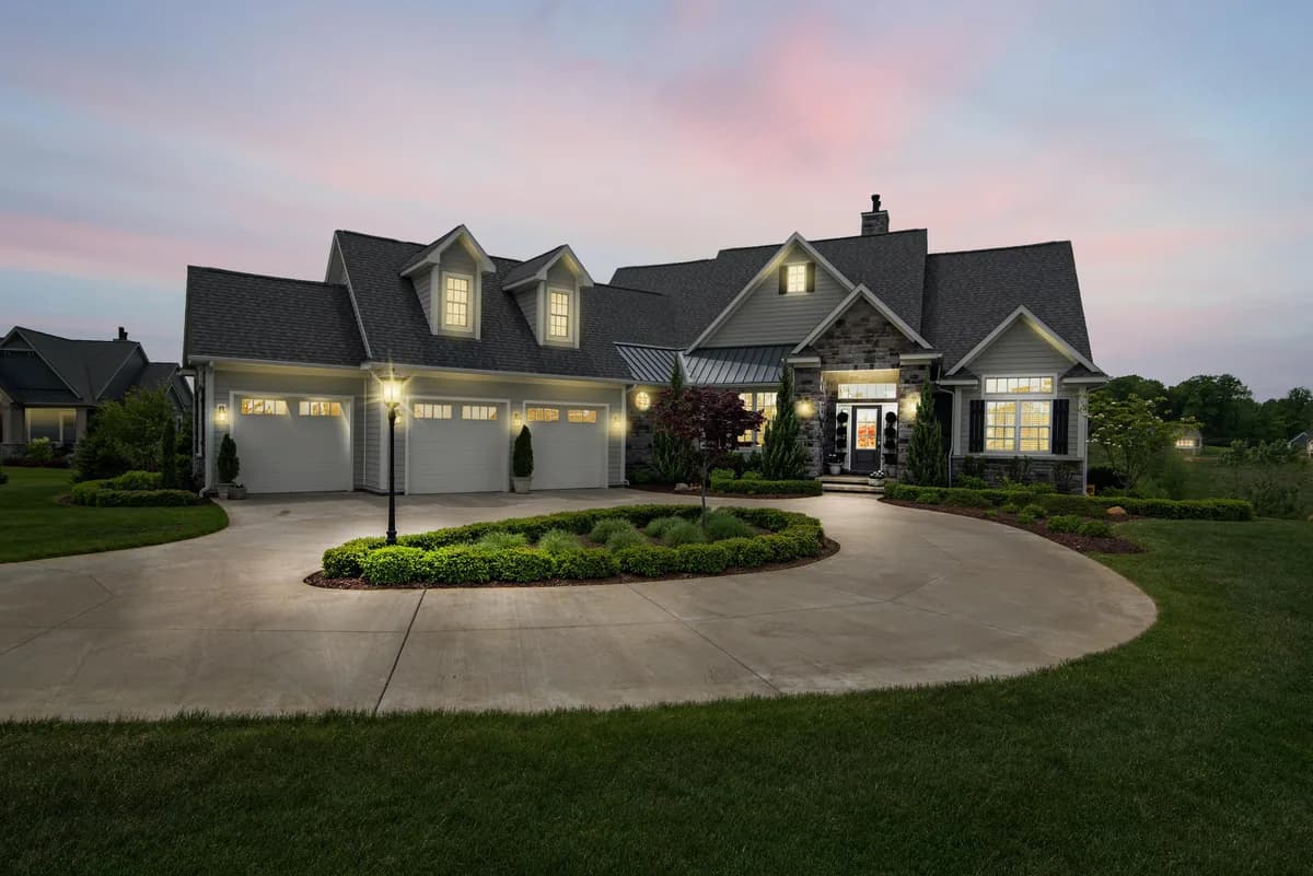 Illuminated residential home exterior with multiple windows and garage doors at twilight