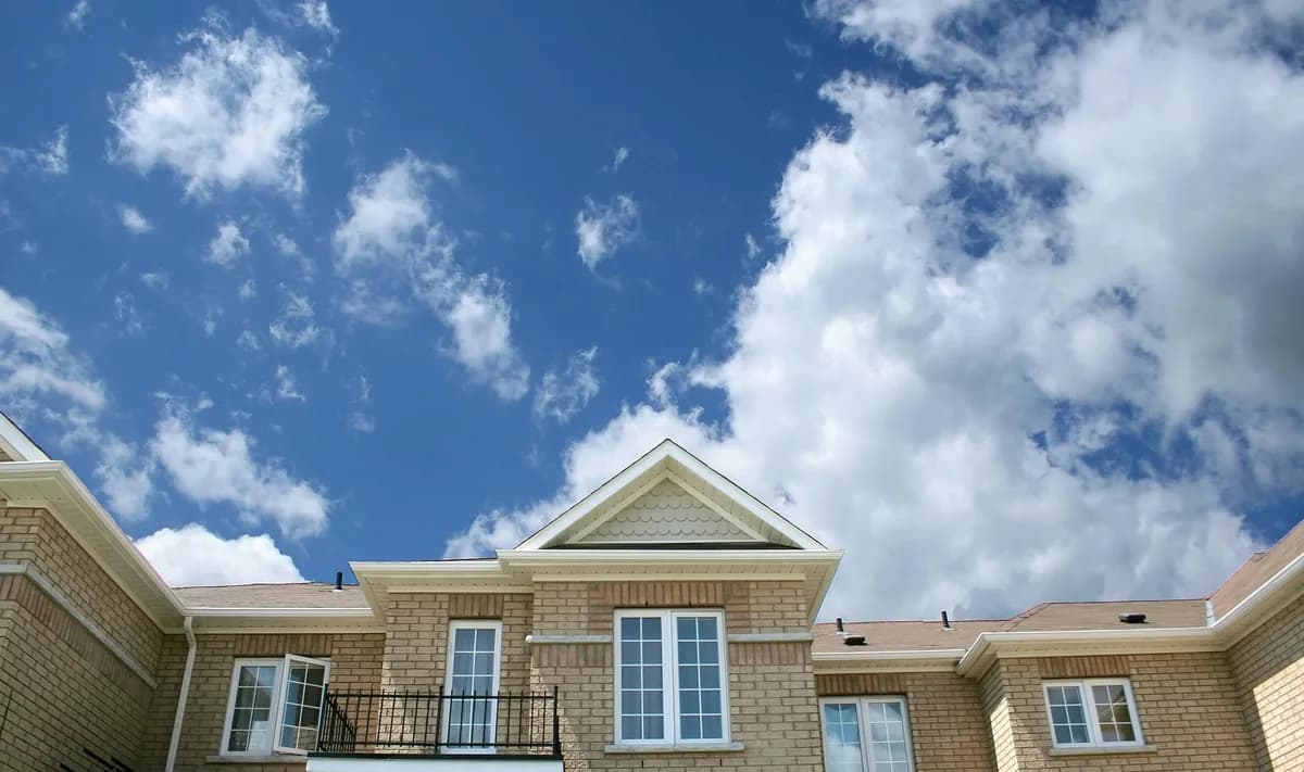 Large residential home with brick exterior and multiple windows under blue sky