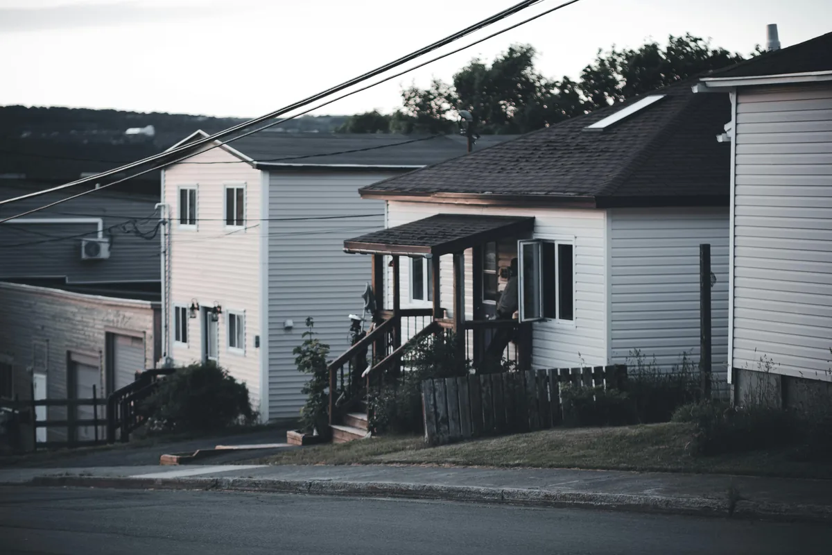 Residential houses with white siding and black-roofed additions along street